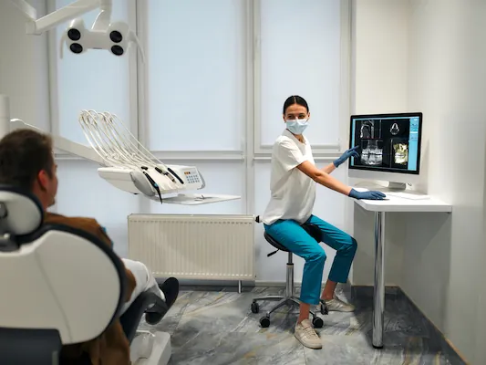 A dental clinician working at an iMac beside the chair