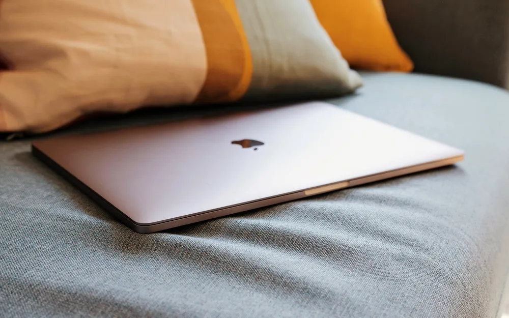 A MacBook resting on a couch at home