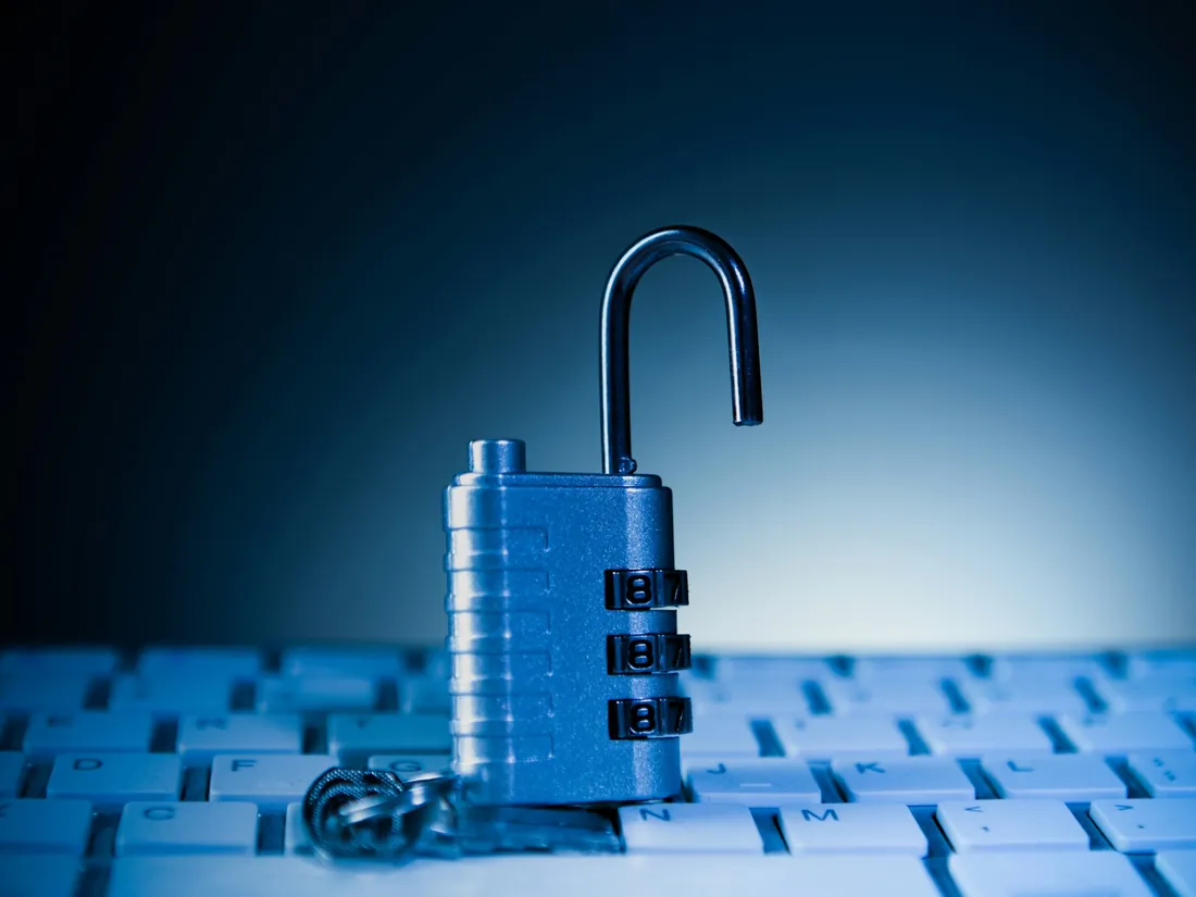 A combination padlock on a computer keyboard in blue light
