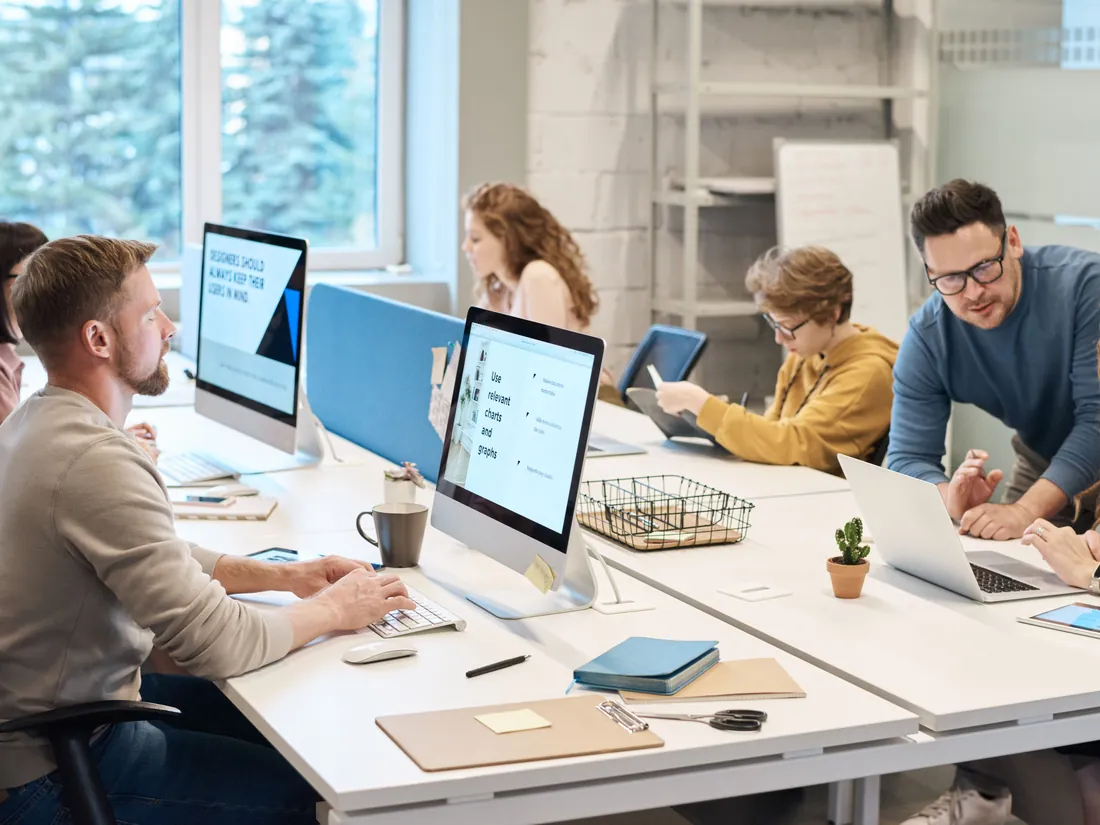 A team working at iMacs and laptops in a bright office