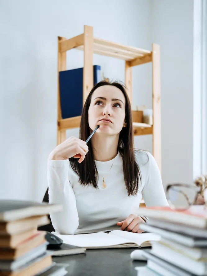 A woman at a desk thinking over a question